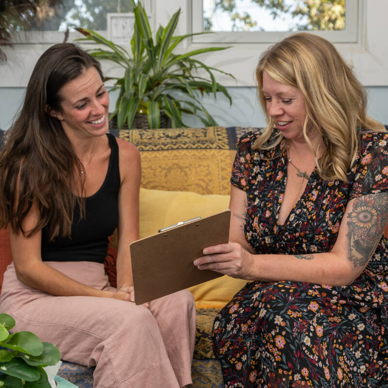 Jaclyn and a client looking over a clipboard together on a couch